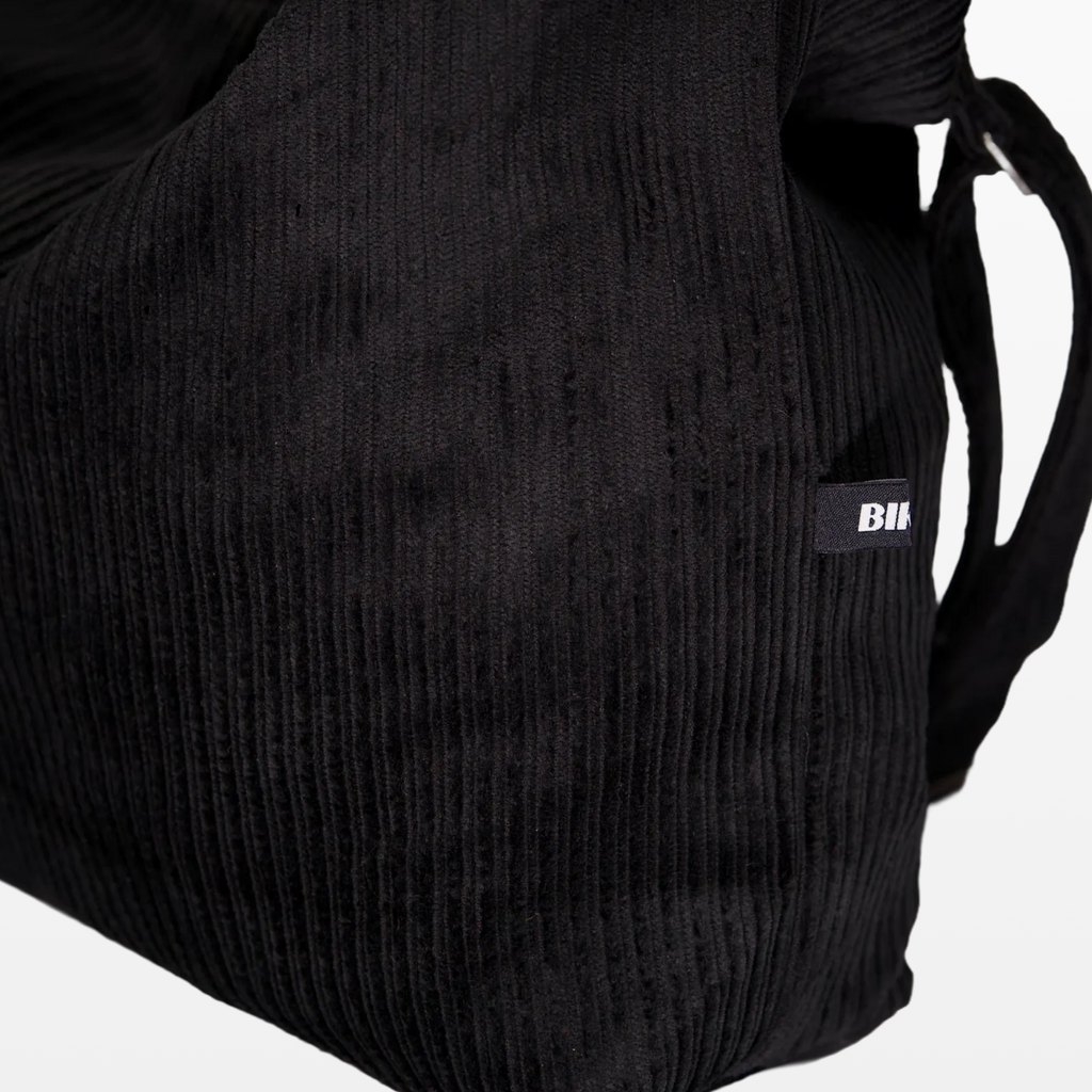 Close-up of the corduroy texture and BIRGER logotype on the sling bag