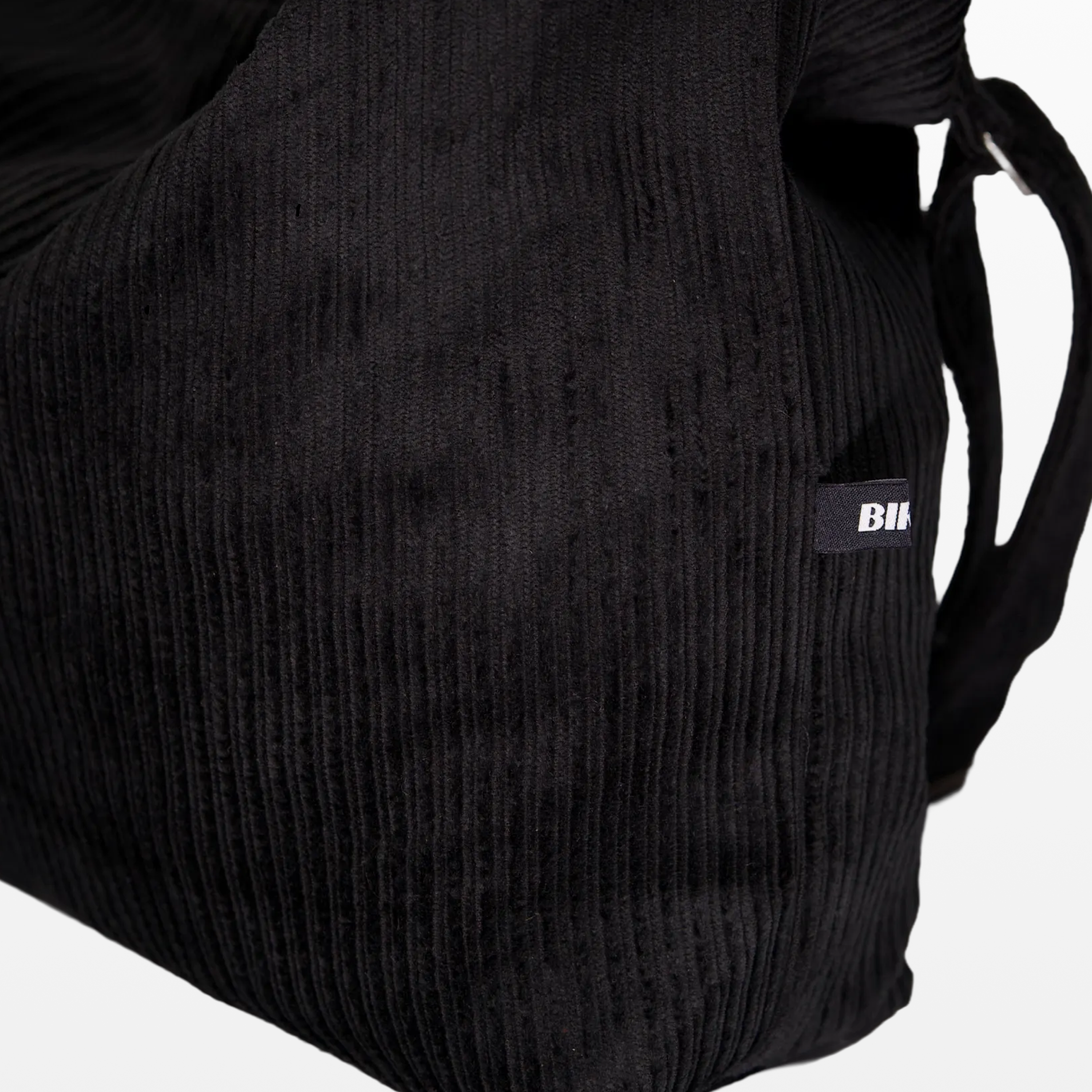 Close-up of the corduroy texture and BIRGER logotype on the sling bag