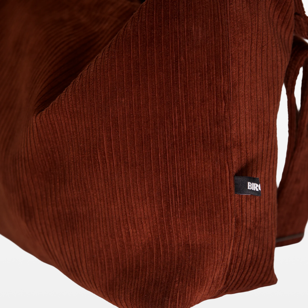 Close-up of the corduroy texture and BIRGER logotype on the sling bag
