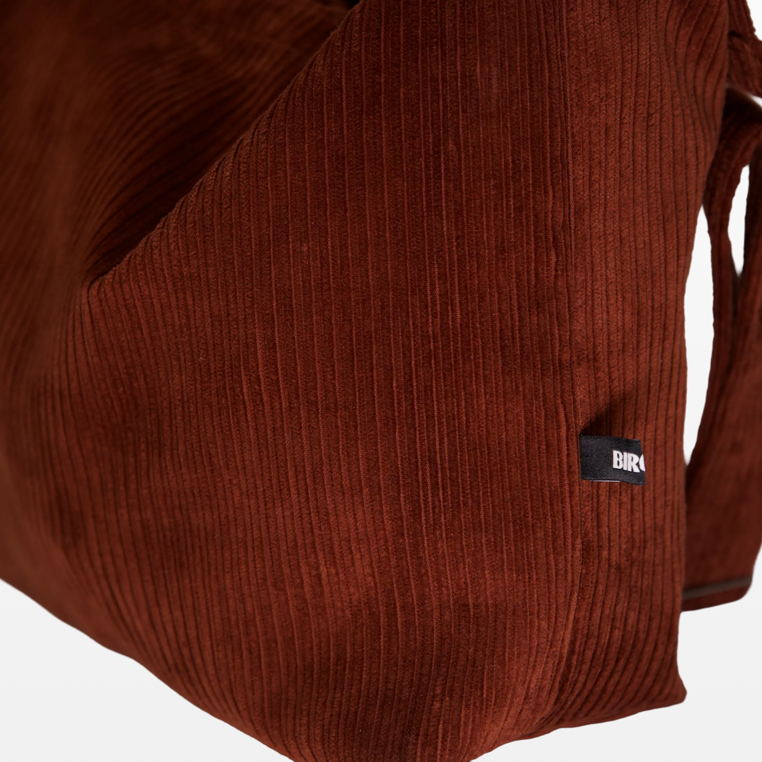 Close-up of the corduroy texture and BIRGER logotype on the sling bag
